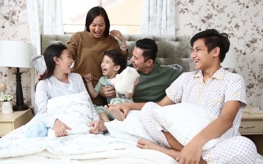 Happy family in bedroom with mom, dad, and 3 children