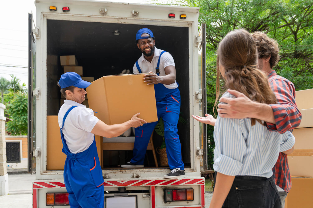 two-men-movers-blue-uniform-lift-cardboard-box-unloading-from-truck-moving-house-service
