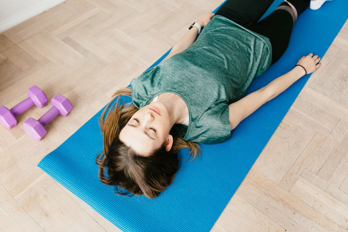 Engage in physical activity like exercise for better sleep l Photo by Photo By: Kaboompics.com: https://www.pexels.com/photo/slim-woman-lying-in-shavasana-pose-on-yoga-mat-4498188/