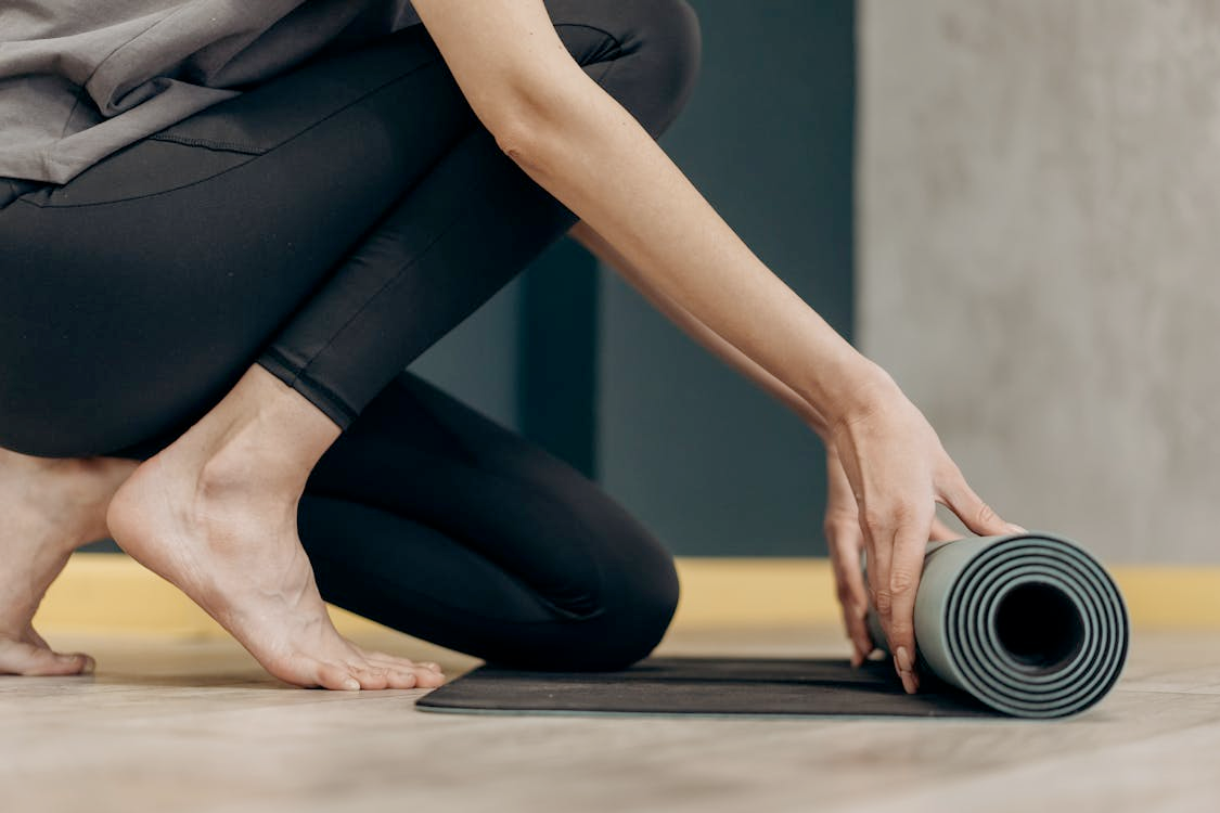 Physical activity promote better sleep at night l Photo by Mikhail Nilov: https://www.pexels.com/photo/woman-unrolling-a-yoga-mat-6740753/