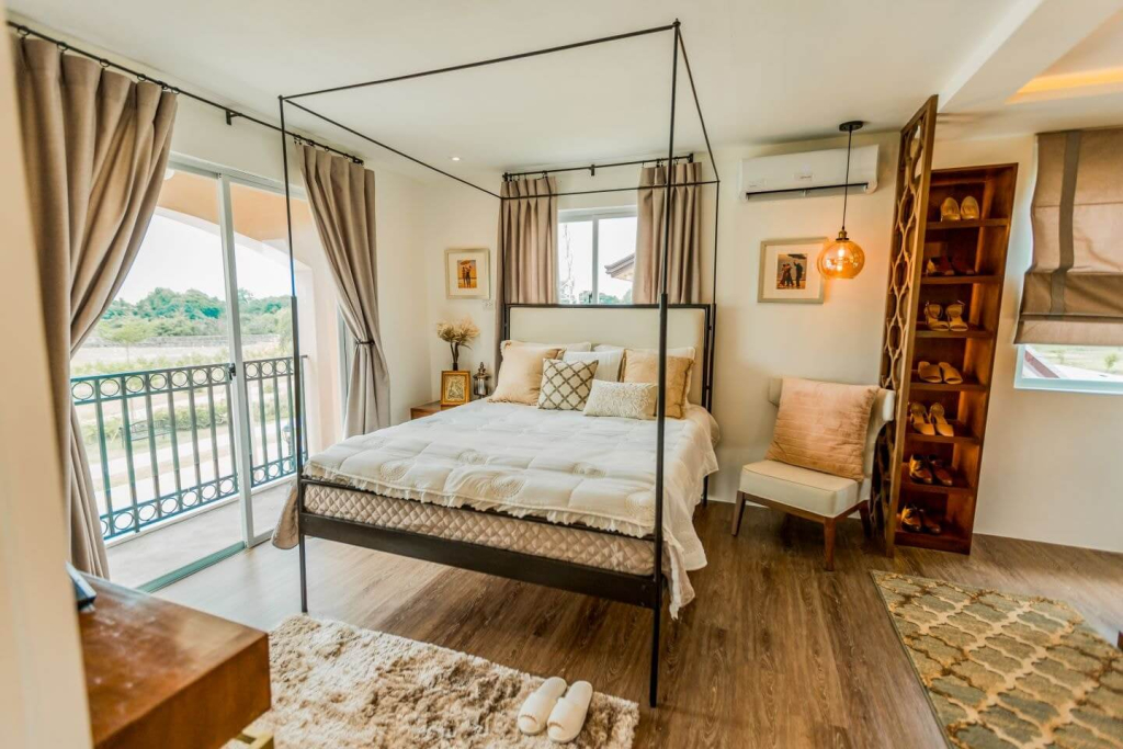 An airy bright bedroom features a four-poster bed with neutral linens, large windows with soft curtains, and patterned motif wallpaper lends a stylish and elegant touch that creates a welcoming and relaxing atmosphere, location icon mumbai