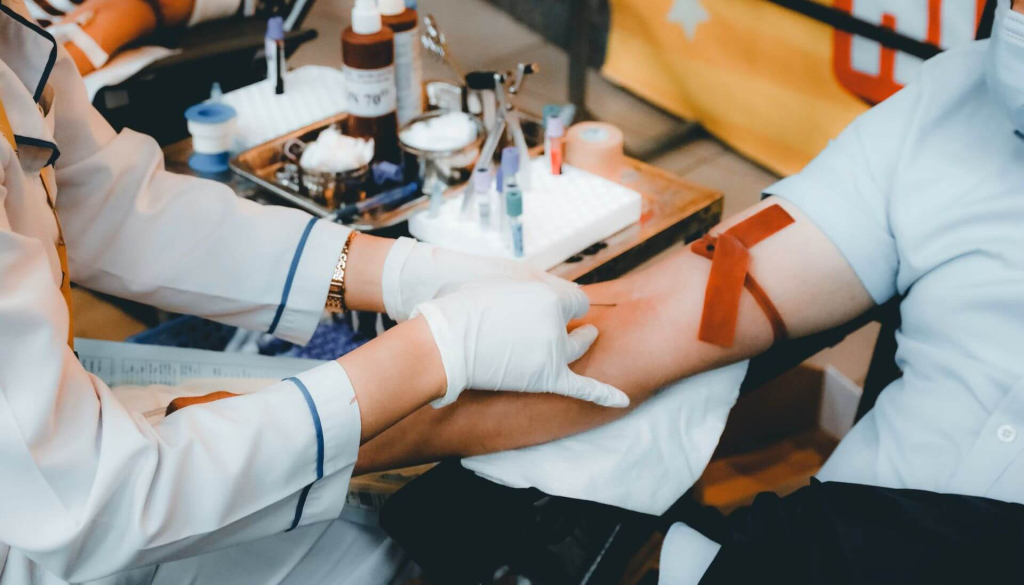 Medical benefits of blood donation l person in white long sleeve shirt sitting on chair
